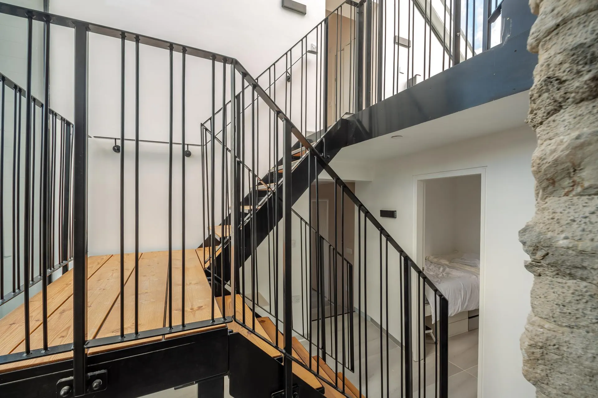 Spiral staircase in the full-height atrium beside exposed stone wall